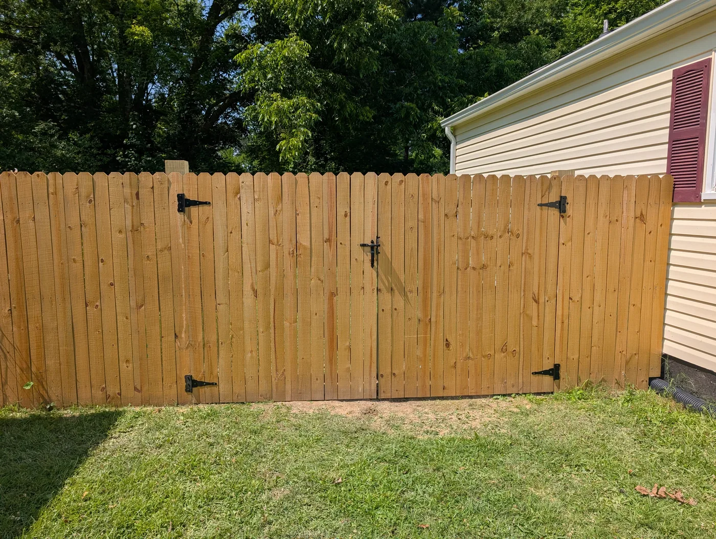 Closed double wooden fence gate with black hinges and latch, completed by Frye Inc.